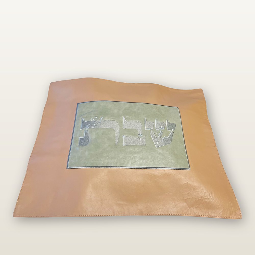 כיסוי חלה מעור בגוון קאמל עם מרכז ירוק-מרווה ורקמת כסף של המילה שבת