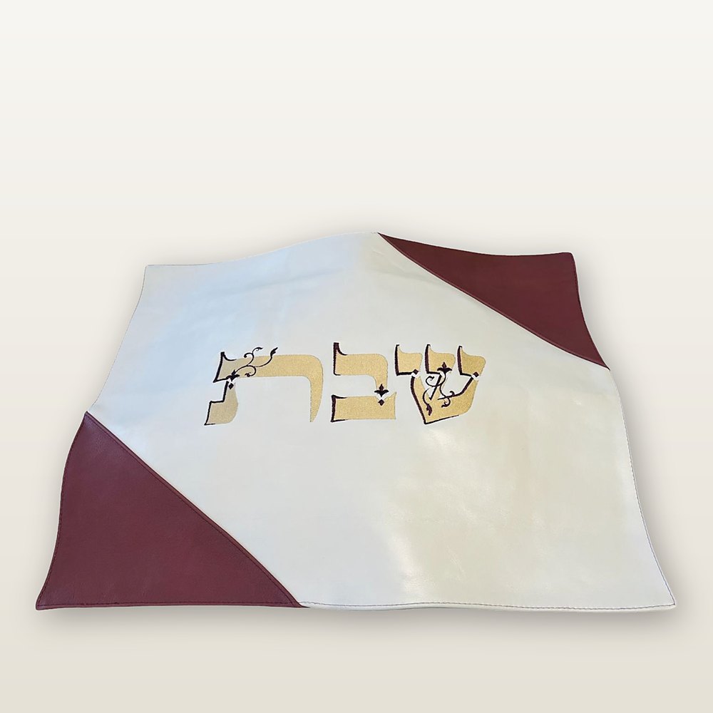 כיסוי חלה מעור לבן עם פינות בורדו ורקמת המילה שבת בזהב עם קווי מתאר כהים