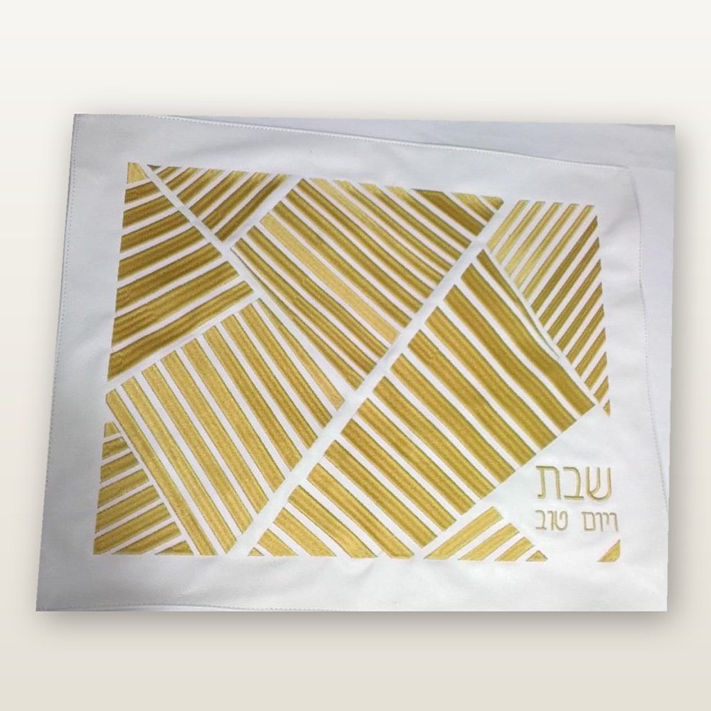 כיסוי חלה מעור בהיר עם רקמת פסים גיאומטריים בזהב וכיתוב שבת ויום טוב בזהב