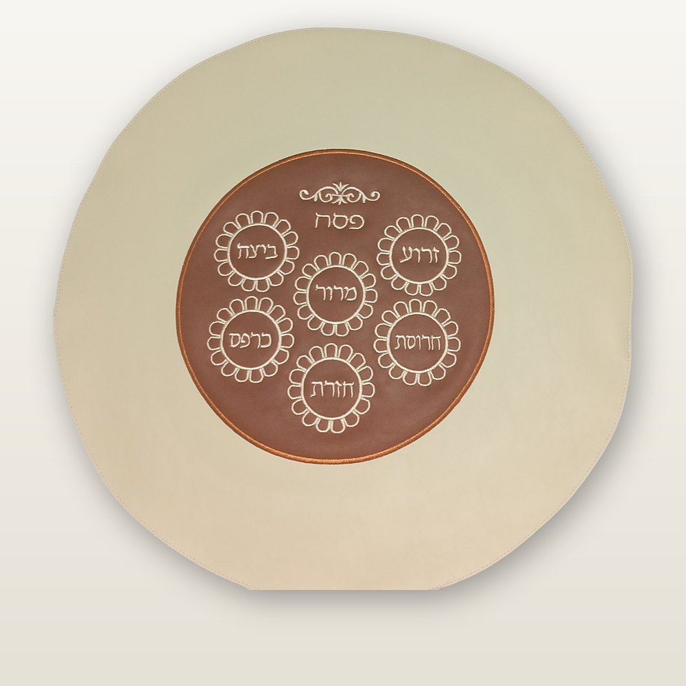 Round matzah cover in cream leather with a rust brown center, six Seder symbols embroidered in cream, copper trim