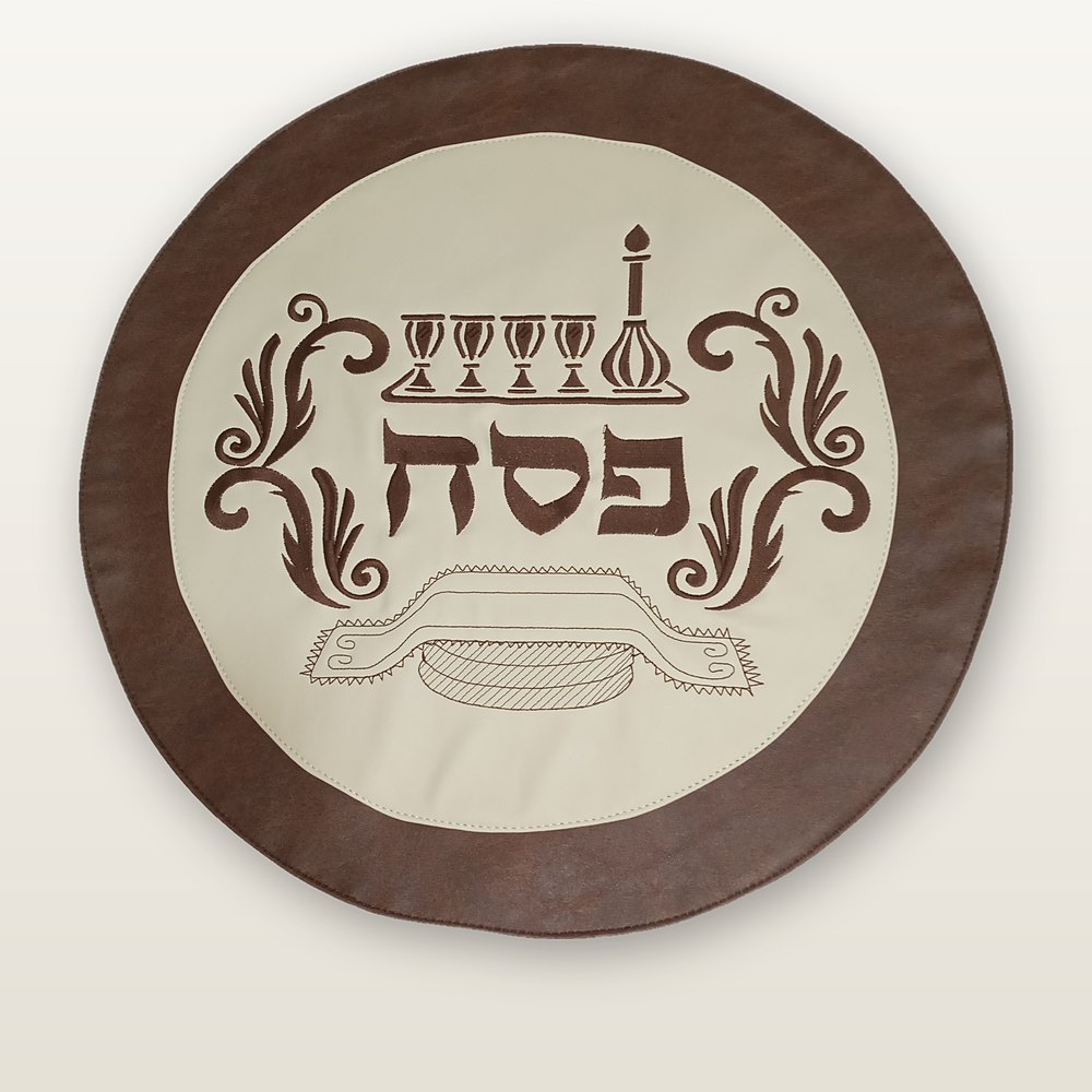 כיסוי מצה עגול, מרכז שנהב וטבעת עור חום, רקמה חומה של ארבע כוסות, קנקן ומצה