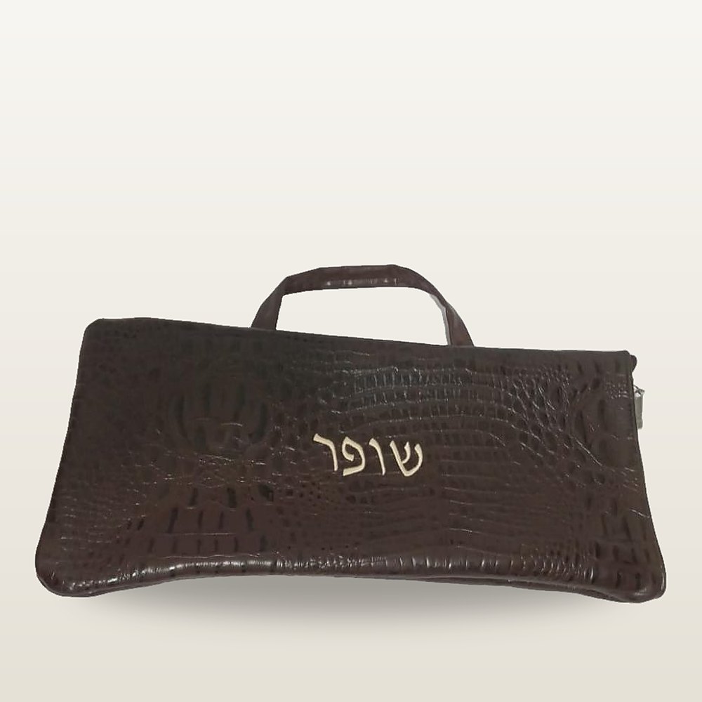 נרתיק לשופר מעור במרקם קרוקו חום כהה, עם שתי ידיות ורקמה בצבע שמנת של המילה שופר