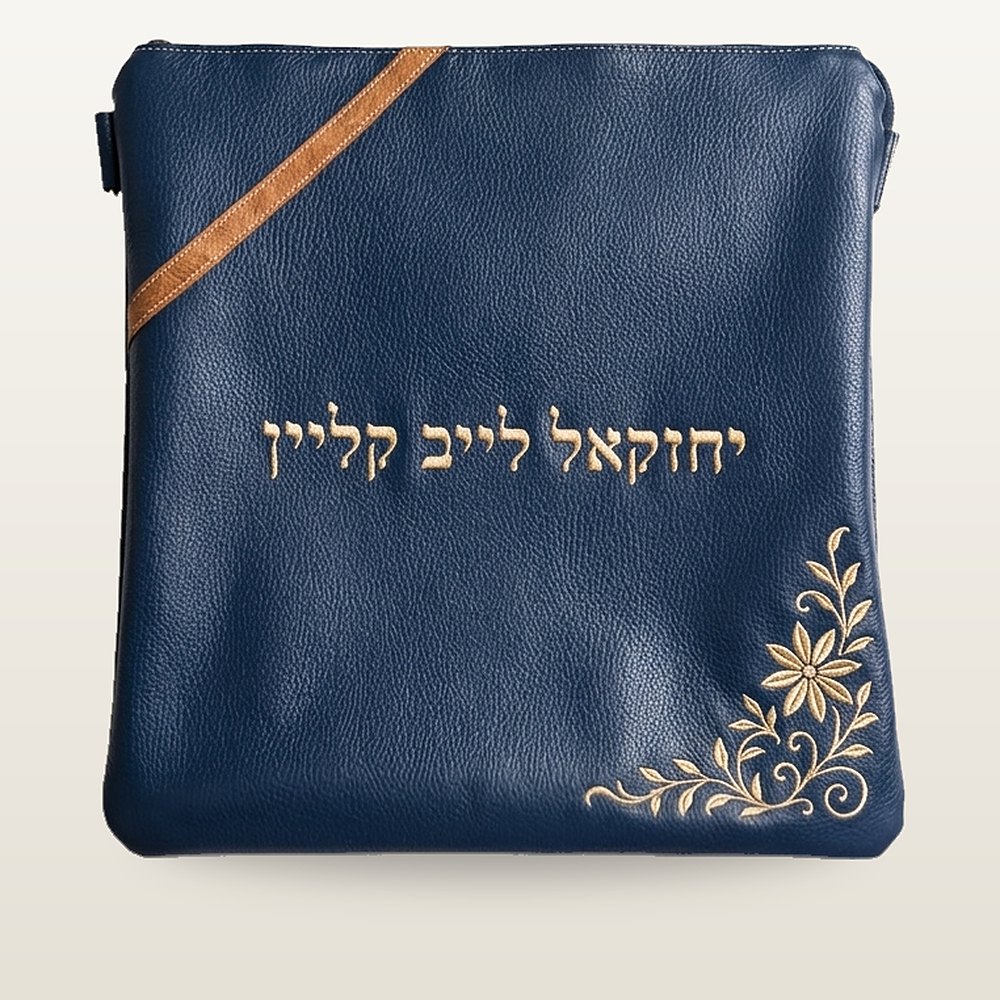 תיק טלית מעור בכחול כהה עם פס אלכסוני בגוון קאמל, רקמה פרחונית זהובה בפינה ורקמת שם אישית בזהב